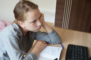 distance learning, the girl attentively watches a video lesson