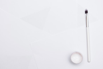 Jar of gouache with white paint and an artist's brush, a white background, copy space