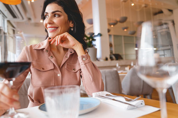 Cheerful young woman sitting at the table in restaurant