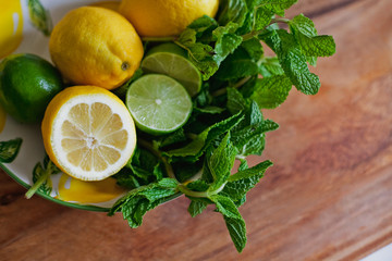 Plate with lemons and limes with mint  on wooden table 