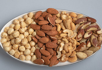 types of roasted nuts in bowl on gray background. Immunity and healthy fats for beauty