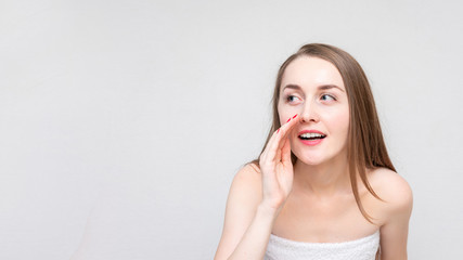 Fototapeta premium Pretty woman telling a secret, white background, copy space, 16:9