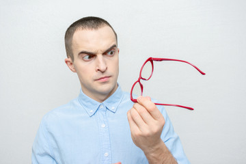 Serious man takes off his glasses, man has poor eyesight, portrait, white background