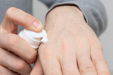 Person uses hand cream, men's hands, close up