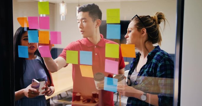 Business people discussing over sticky notes in a modern office