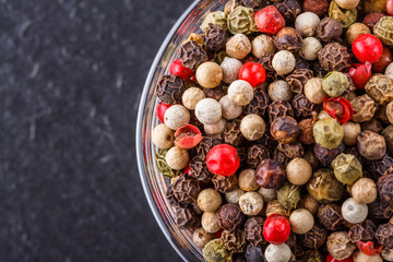 mix of peppercorns on a dark stone background