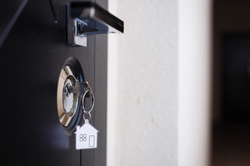 Silhouette of door keys hanging on the open door with blurred background