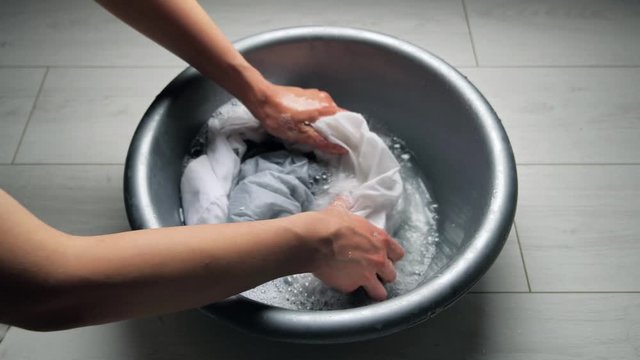 A woman hands washing white laundry in a plastic basin with washing powder 4k