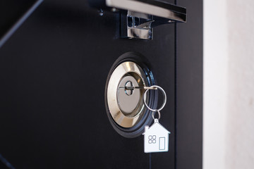 Silhouette of door keys hanging on the open door with blurred background