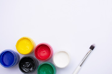 Bottle of different colors gouache paints and artist brush, white background, copy space, top view
