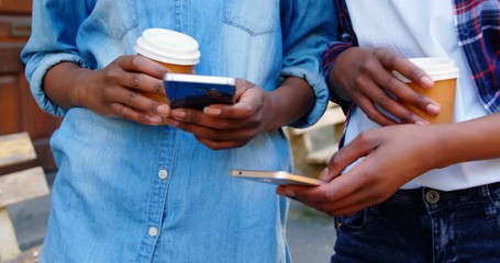 Twin sisters using mobile phone in the city - Powered by Adobe