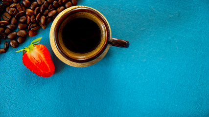 A Cup of morning coffee, strawberries, coffee beans.