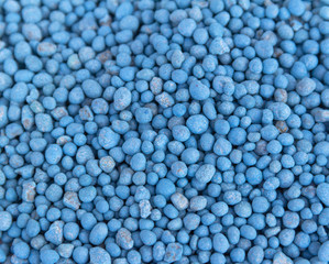 Blue different shape chemical fertilizer granules as abstract background.