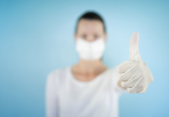 Woman with thumbs up wearing facemark and gloves. Coronavirus protection concept