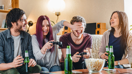 Young group of friends having fun while playing video games at home