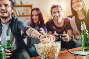 Close up of young man taking popcorn while friends playing video games © InsideCreativeHouse