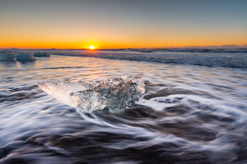 Golden ice on the black beach near Jokulsarlon glacier lagoon, daimond beach, South Iceland.