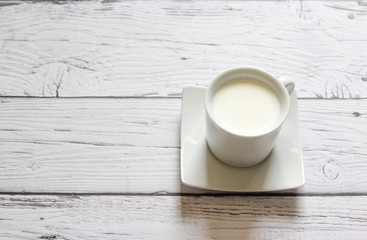 Cup of warm milk on a wooden background. White Cup with milk.