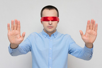 Man with a blindfold is looking for a way out of a difficult situation, red bandage, portrait,...