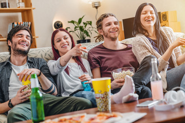 Group of friends having wonderful time watching television at home