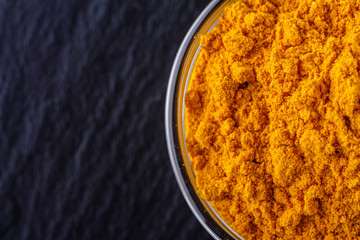 natural turmeric powder on a dark stone background