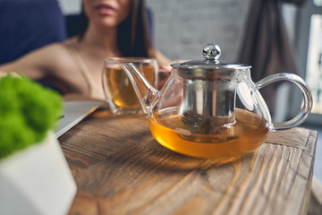 Young woman sitting at the table with glass teapot