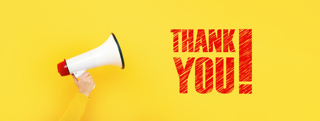 megaphone in hand and inscription thank you on a yellow background, concept of thanks for...
