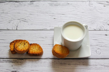 Cup of milk and bread crumbs on a wooden background. Healthy breakfast.