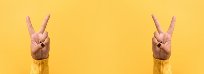 Hand gesture V sign for victory or peace sign over yellow background