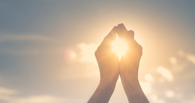Woman's hands holding the sun at dawn. Freedom and spirituality concept. 
