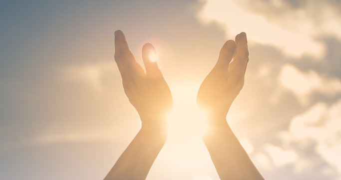 Woman hands holding the sun at dawn. Freedom and spirituality concept. 