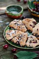 Scone with cherry on old wooden table. Rustic style photo.
