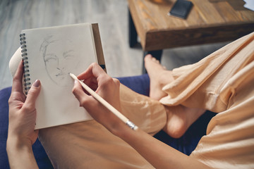 Young lady drawing in notebook at home