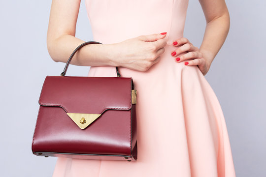 Young woman in pink dress with handbag, women's hands, cropped image, close-up