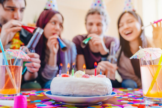 Close up photo of birthday cake with celebrating friends on background