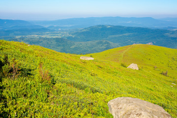 Obraz premium mountain summer landscape. meadow with Giant sharp stone among the grass on the edge of a hill