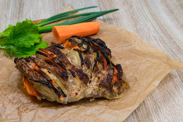 Oven-baked pork slices with vegetables on a wooden table, background
