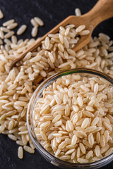 raw brown rice on a dark stone background