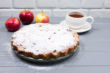 Homemade baked apple pie, in a plate, on a gray wooden table, ready to eat. Place for an inscription.