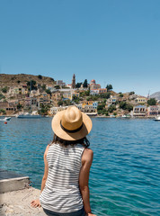 Woman in hat on the harbour of Symi, Greece