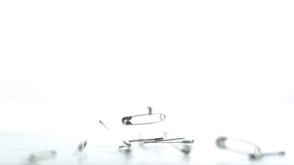 Safety pins falling on white background - Powered by Adobe