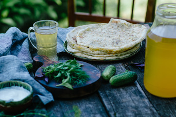 Johnny cake with cheese with greens. Lunch with kvass and tortillas with greens on a table at nature.