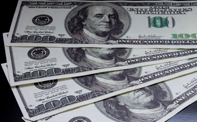 fan of hundred-dollar four bills on a black background