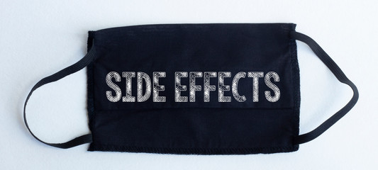 Black disposable protective mask with SIDE EFFECTS text on black background.