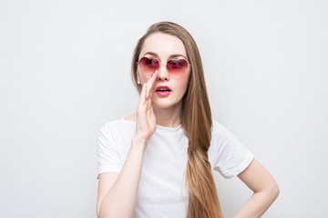 Young woman heart-shaped glasses softly gossips, portrait, white background