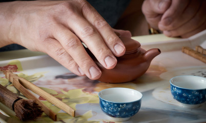 Pouring tea from teapot into cups.