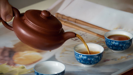 Pouring tea from teapot into cups.