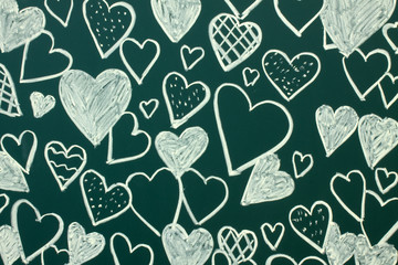 Hearts drawn in white chalk on a green blackboard close-up