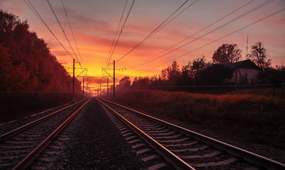 Fototapeta na wymiar Rails extending into the distance, illuminated by the sunset sky.