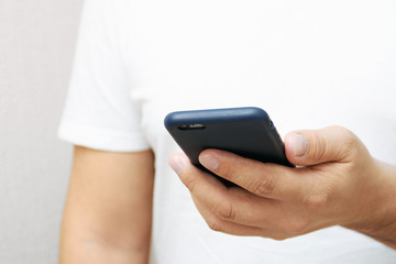 A person is holding a phone and tapping the screen on a white background with copy space. Concept of lifestyle business and Internet technologies in the office